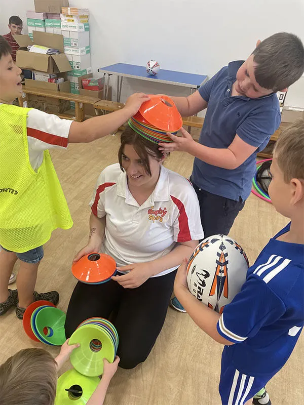 Coach helping a young child with a rugby ball