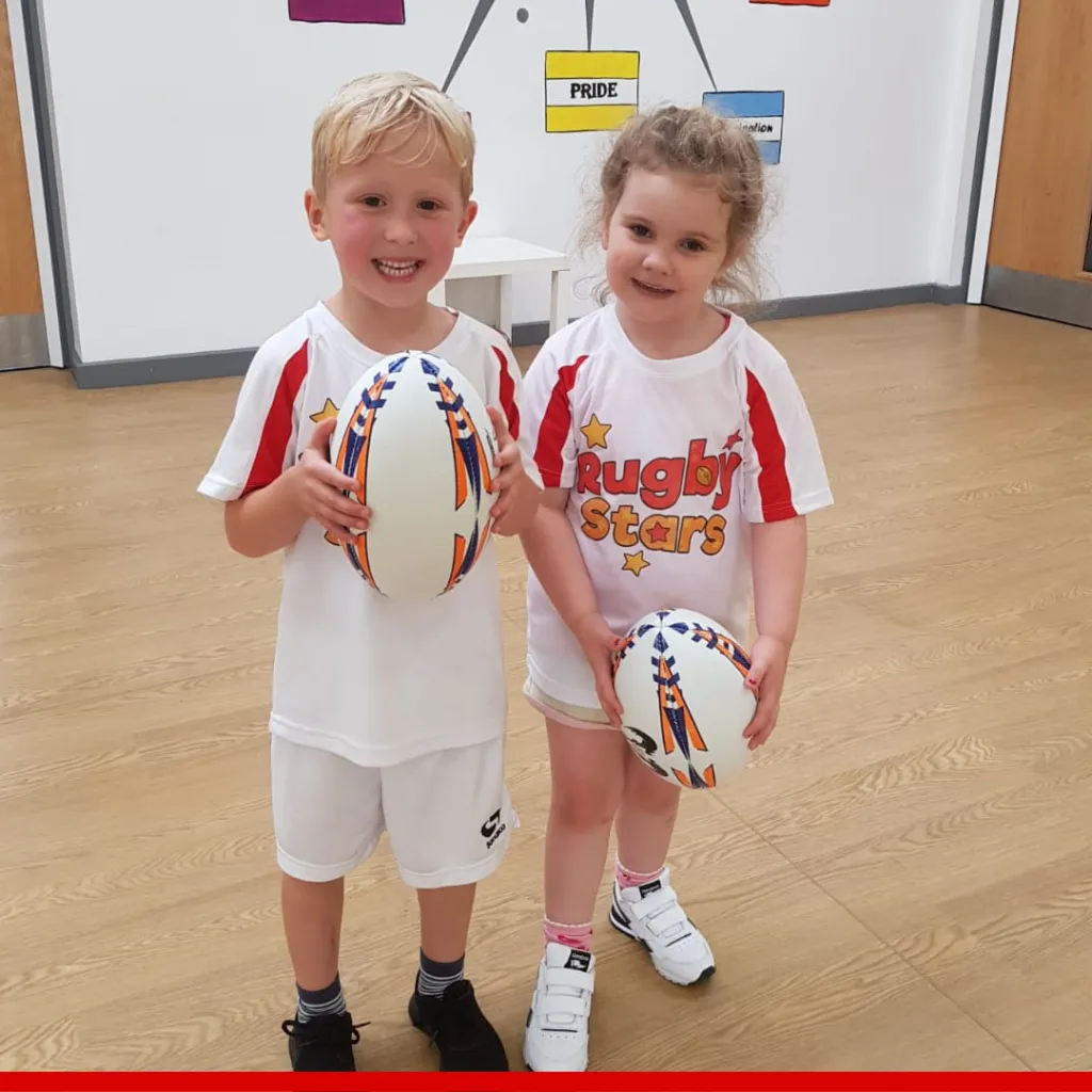 Two happy children in Rugby Stars kits holding rugby balls